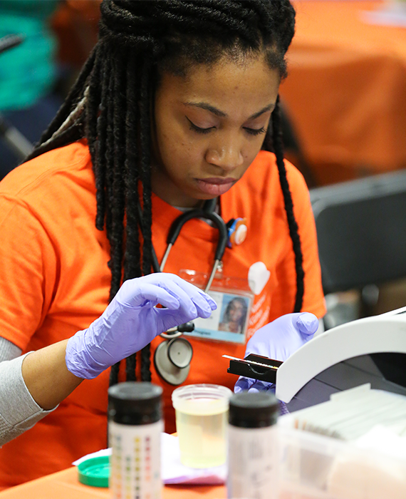 Black nurse runs a test on a urine sample