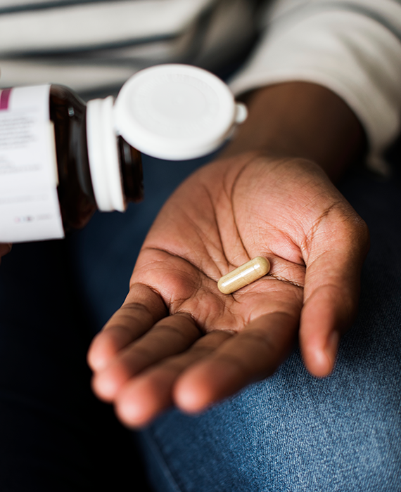 Close up of hands holding a medication bottle and holding a single pill
