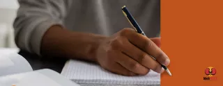 Image of a hand holding a pen, hovered over a blank notebook