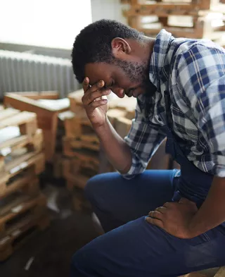 A man in pain, holding his stomach and head. 