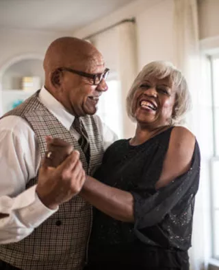 Photo of smiling couple dancing in their living room