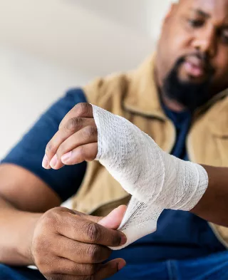 Black man in background wrapping his hand in the foreground. 