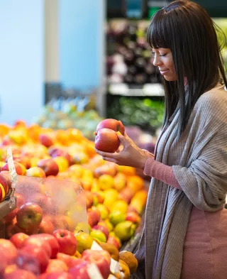 Young woman grocery shopping and comparing produce