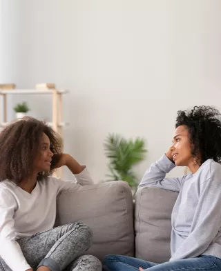 Two women seated on a sofa, having a deep conversation
