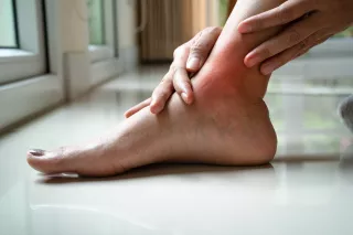 Woman's hands holding swollen ankle